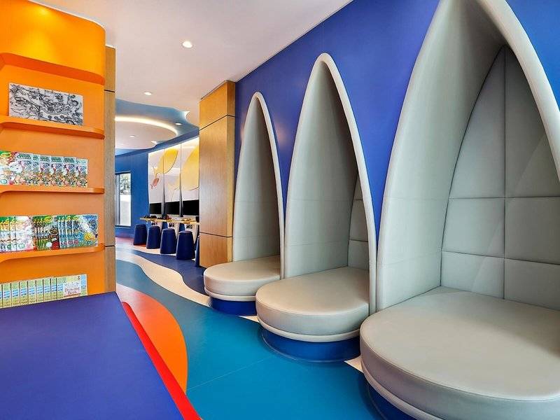 Der Kinderbereich im Hilton Dubai Palm Jumeirah mit blauen und orangefarbenen Wänden, Bücherregalen und Sitznischen.