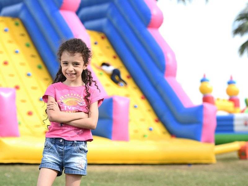 Mädchen steht lächelnd vor einem aufblasbaren Spielplatz