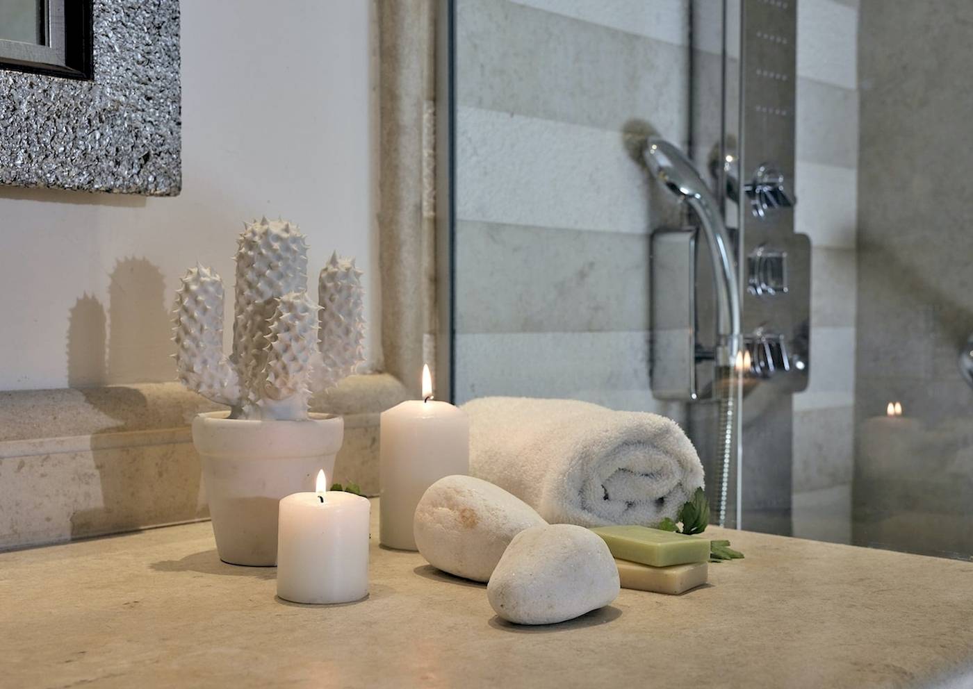 Badezimmer im Pilot Beach Resort mit Kerzen, Kaktus und Handtüchern.