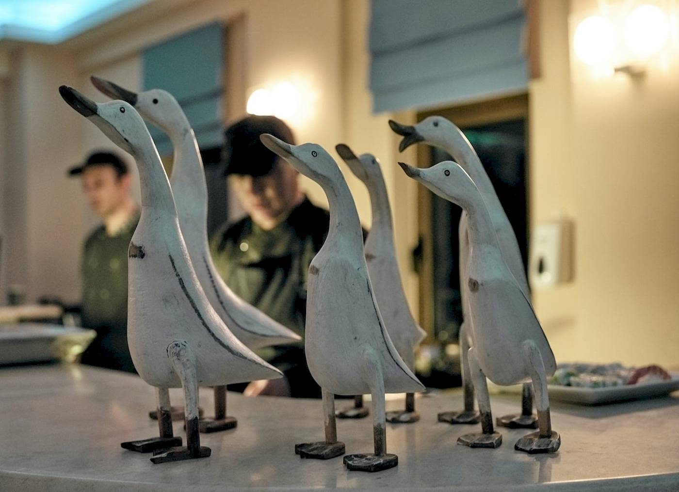 Sechs weiße Enten-Skulpturen auf einem Tisch im Pilot Beach Resort.