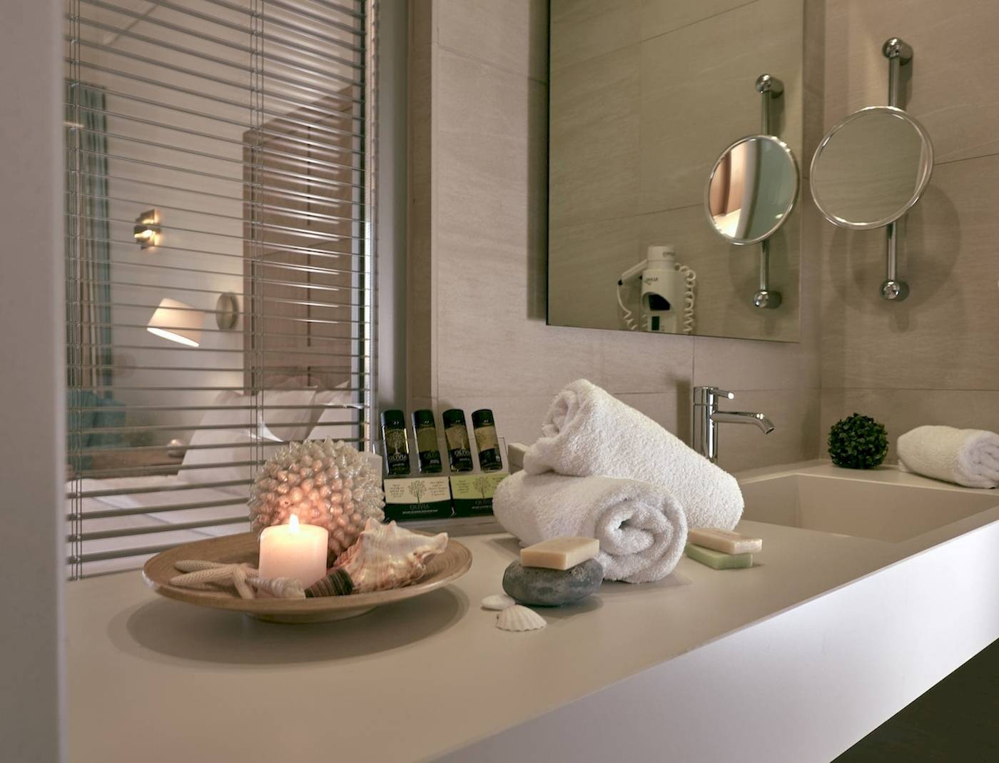 Badezimmer im Pilot Beach Resort mit heller Einrichtung, Handtüchern, Kerze und Föhn