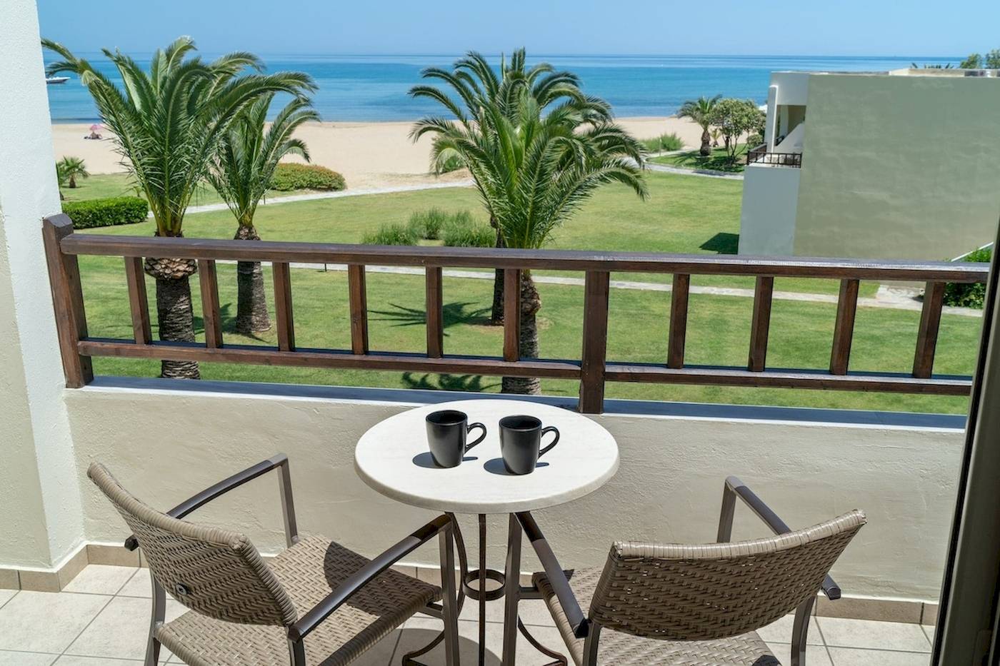 Balkon mit Blick auf das Meer vom Pilot Beach Resort mit zwei Tassen auf dem Tisch.