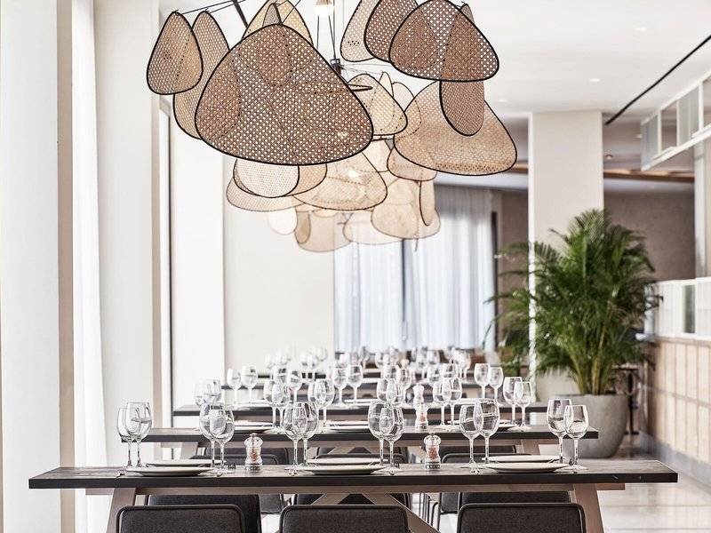 Foto des Mare Paphos Hotels Innenbereichs mit eingerichteten Tischen und Stühlen sowie einer großen Deckenlampe.