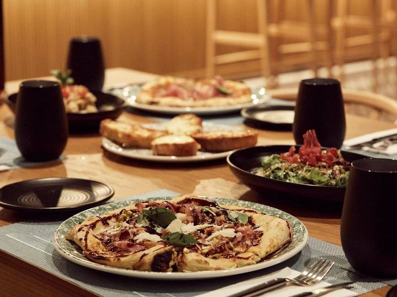Foto von mehreren Gerichten auf einem Tisch im Mare Paphos Hotel, darunter Pizza, Salat und Getränke.