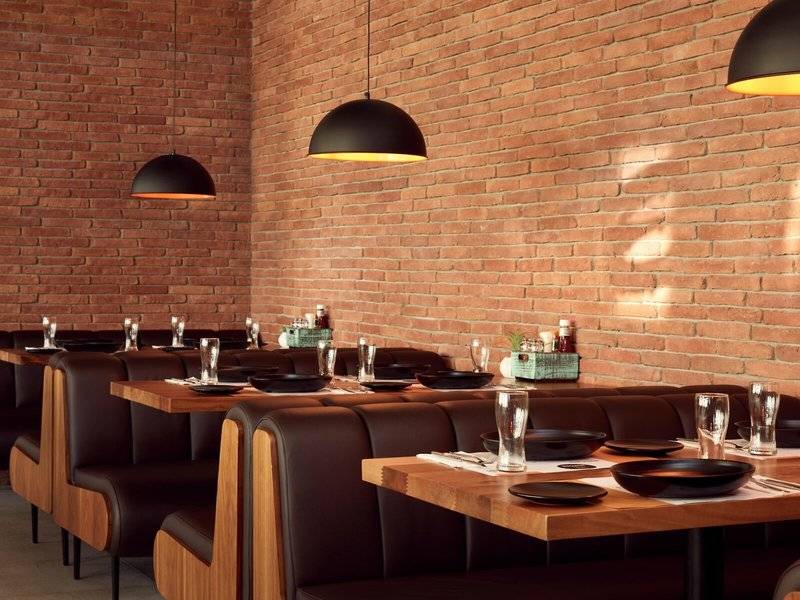 Innenbereich des Mare Paphos Restaurants mit roten Ziegelwänden und schwarzen Leuchten