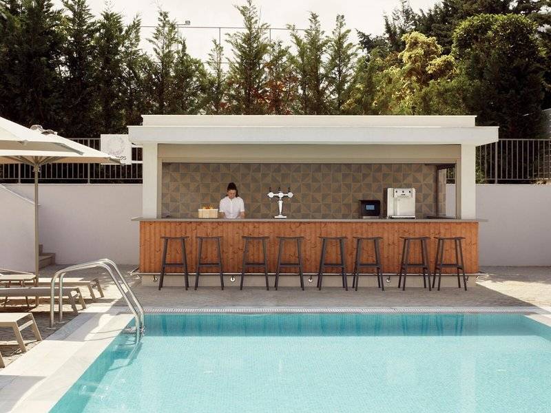 Poolbar des Mare Paphos Hotels mit einer Bedienung und Sonnenschirm.