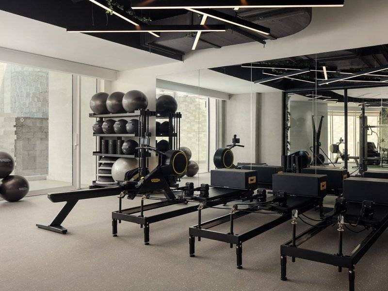 Fitnessstudio im St. Regis Al Mouj Muscat Resort mit Pilatesgeräten und Hanteln.