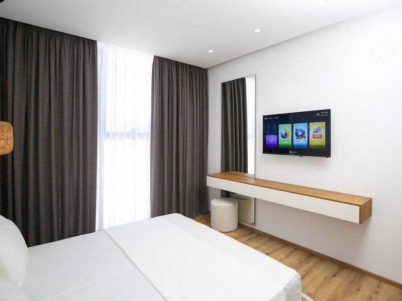 Innenansicht eines Zimmers im Oricon Coast Luxury Resort mit einem Bett, Fernseher, und Nachttisch.