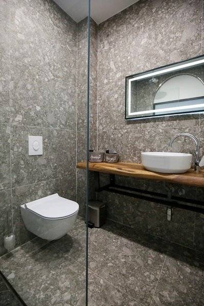 Badezimmer des Oricon Coast Luxury Resort mit grauen Wänden und Bodenfliesen, einer Dusche, einem Waschbecken und einem Toilettensitz.