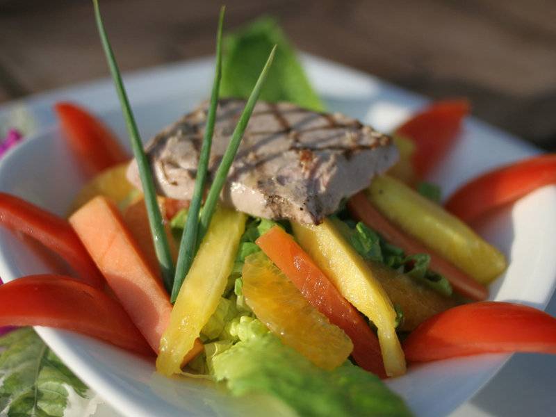 Salat mit verschiedenen Früchten, Gemüse und Fleisch auf einem weißen Teller.