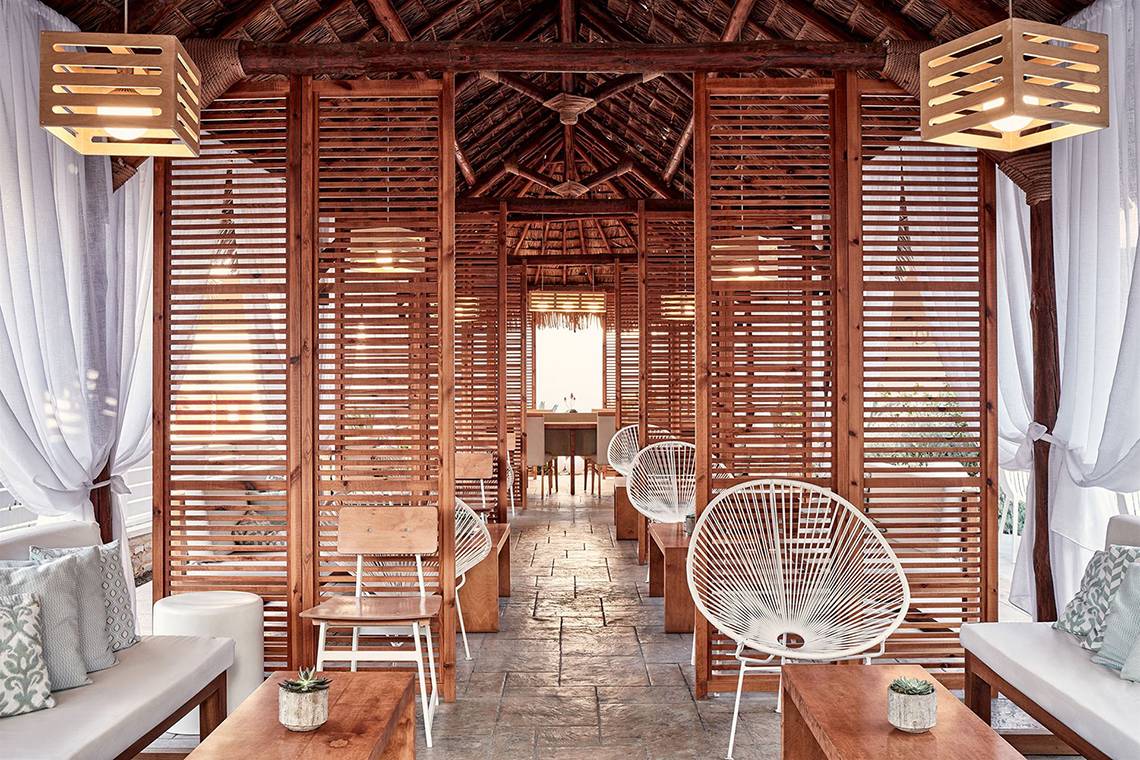 Innenbereich der Holzlounge im Atlantica Caldera Palace Hotel mit weißen Stühlen und Tischen.