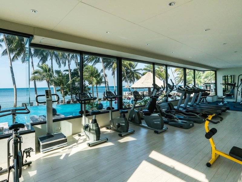 Fitness-Center im KC Grande Resort Koh Chang mit Aussicht auf das Meer und Palmen.