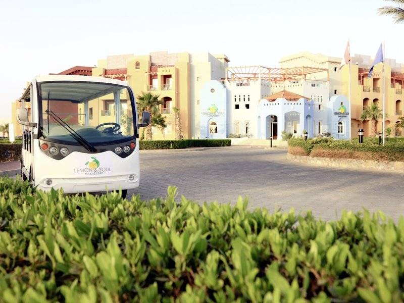 Ein weißer Bus von Lemon & Soul Garden Makadi Bay Hotel fährt vor einem Gebäude.