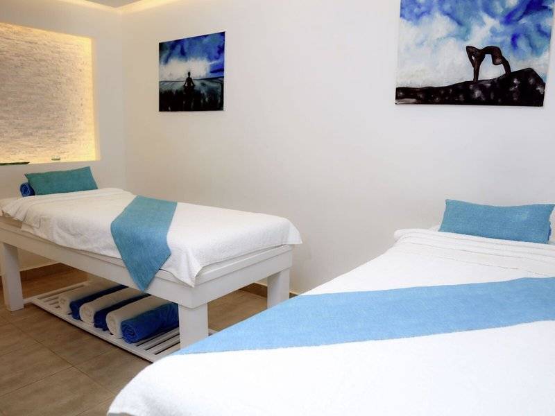 Zwei Betten im Spa-Bereich des Lemon & Soul Garden Makadi Hotels mit weißen Laken und blauen Kissenbezügen.