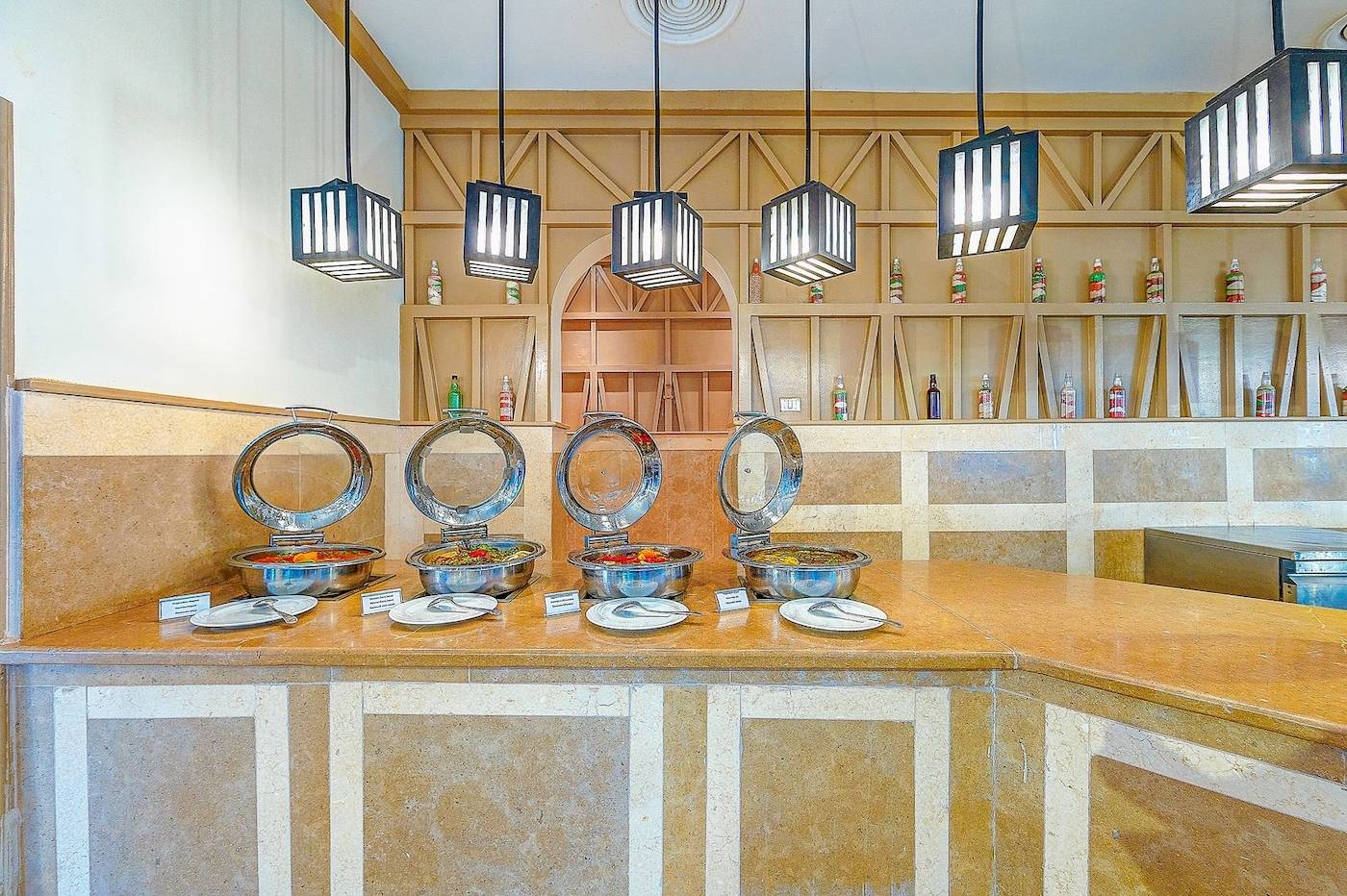 Buffet-Tisch im Grand Makadi Hotel mit Speisen in Metallschüsseln und hängenden Laternen.