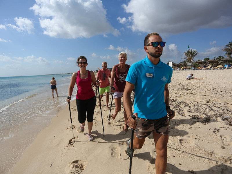 Gruppe von Gästen und ein Betreuer wandern am Strand des Paradis Palace Hotels