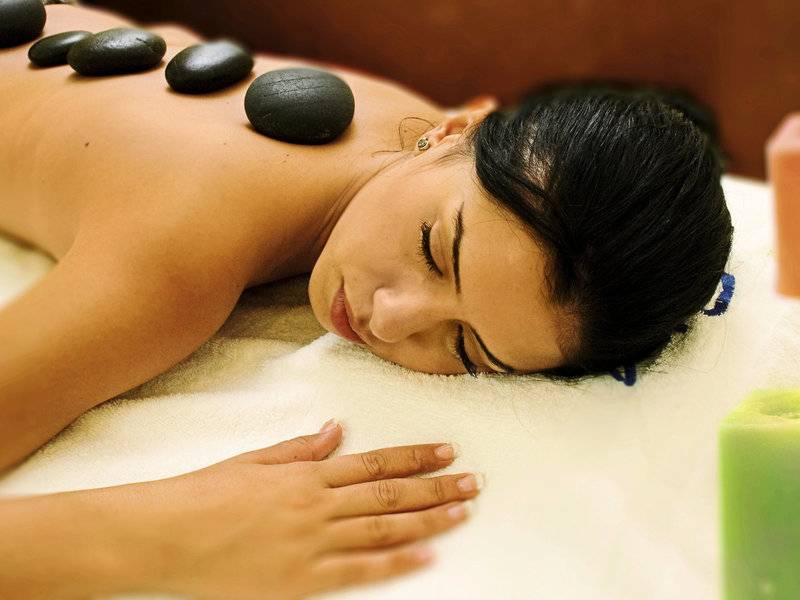 Frau genießt eine Massage mit Steinen auf dem Rücken im Hotel Paradis Palace