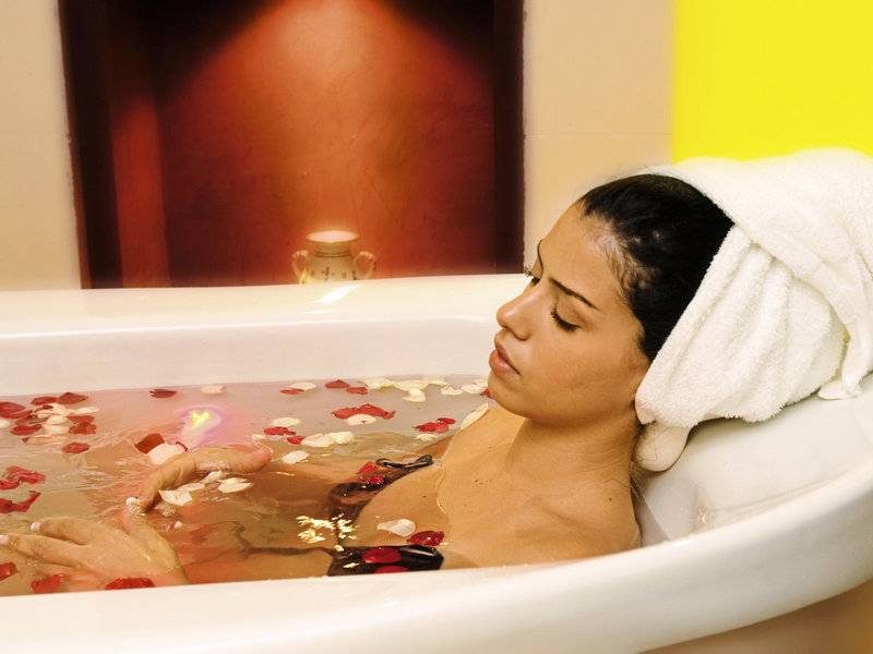 Frau genießt ein Bad mit Rosenblättern im Paradis Palace Hotel