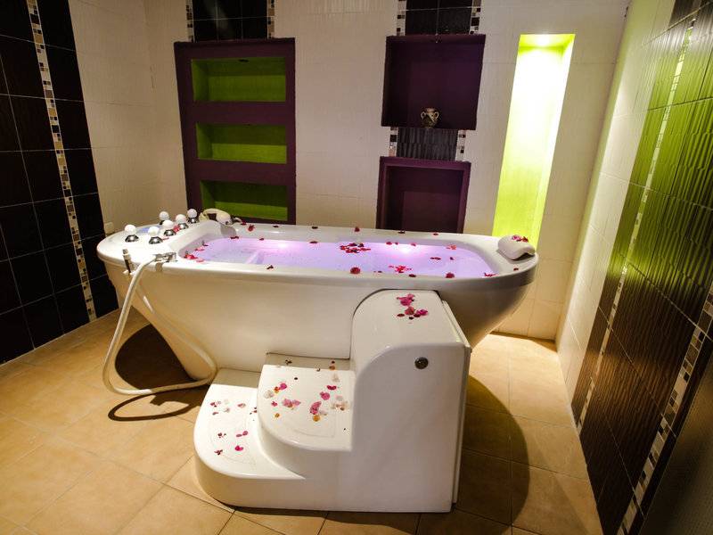 Badezimmer im Paradis Palace mit einer Badewanne voller Rosenblättern und einem gefliesten Boden.