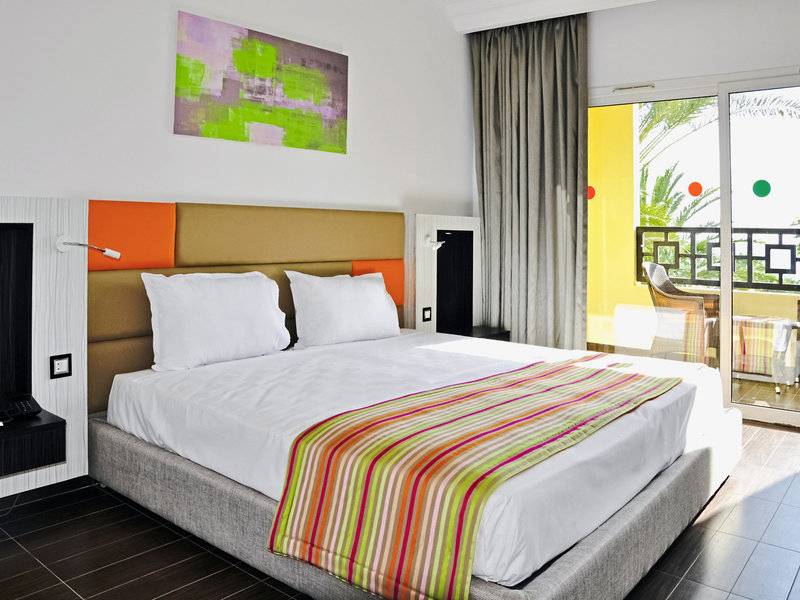 Das moderne Zimmer im Paradis Palace Hotel mit einem großen Bett und buntem Bettdecken.