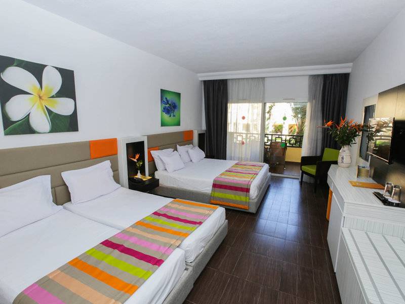 Doppelzimmer im Paradis Palace Hotel mit zwei Betten, farbenfroher Bettwäsche und Balkon.