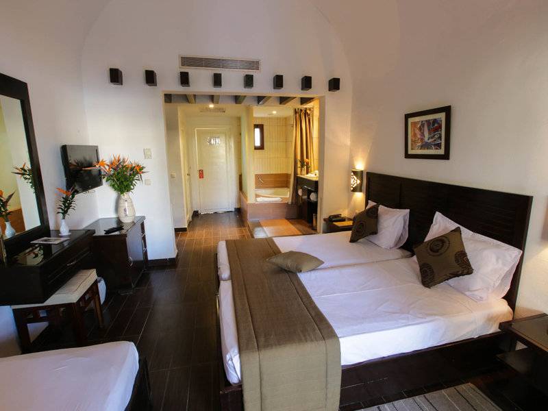 Doppelbettzimmer im Paradis Palace Hotel mit moderner Einrichtung und Blick auf das Badezimmer.