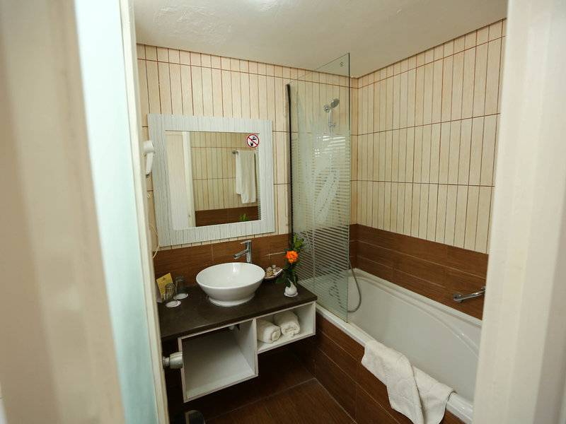Badezimmer im Paradis Palace Hotel mit Badewanne, Waschbecken und Spiegel.