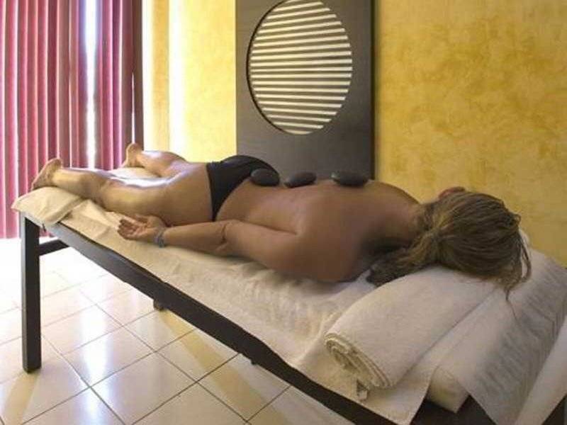 Frau genießt eine Massage mit heißen Steinen im Wellnessbereich des Nour Palace Resort & Thalasso.