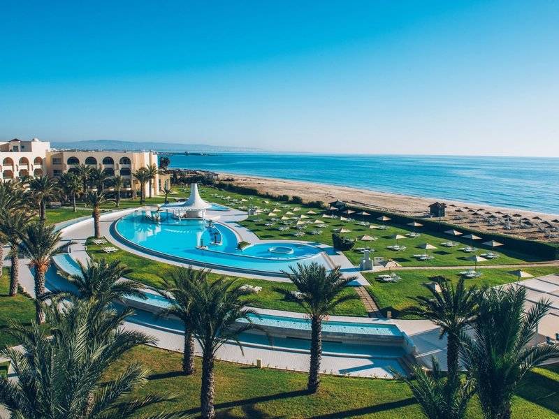 Außenansicht des Iberostar Waves Averroes Resorts mit Pool, Palmen und Meer