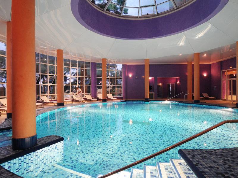 Innenpool im JAZ Tour Khalef Hotel mit blauen Fliesen und orangefarbenen Säulen.