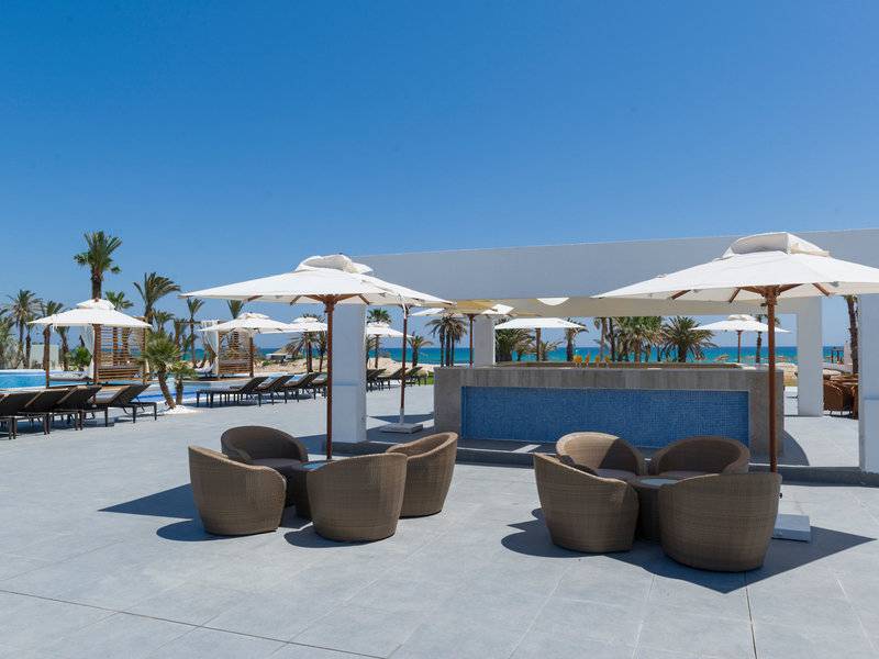 Außenbereich des JAZ Tour Khalef Hotels mit Pool, Sonnenliegen, Schirmen und Stühlen.