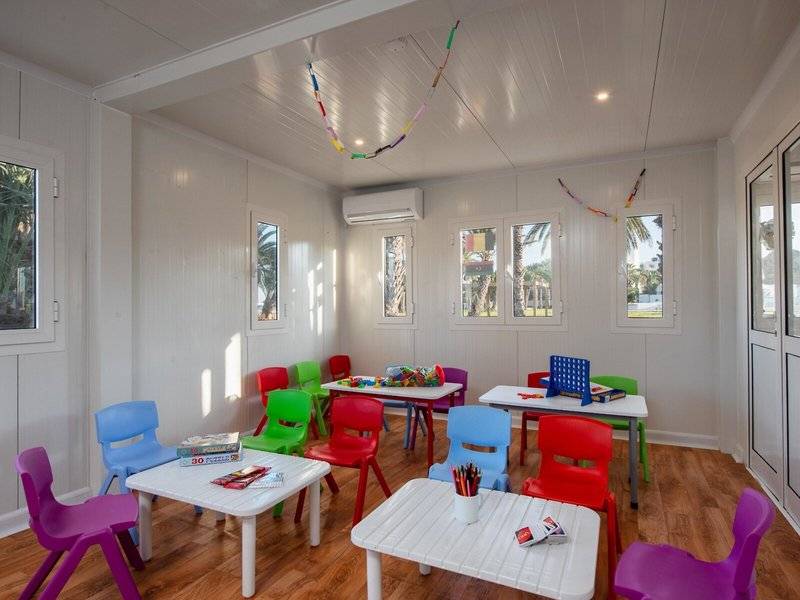 Farbige Kinderstühle und Tische im JAZ Tour Khalef Kinderzimmer, bunte Dekorationen an der Decke.