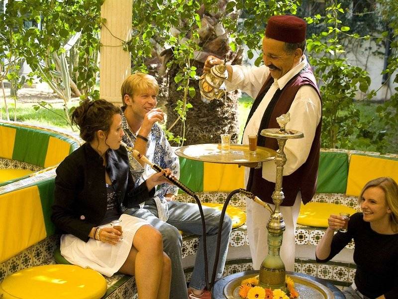 Gäste im Sahara Beach AquaPark Resort sitzen und rauchen Shisha an einem runden Tisch.