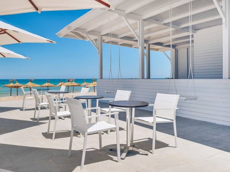 Außenbereich des Iberostar Selection Kuriat Palace Hotels mit weißen Tischen und Stühlen.
