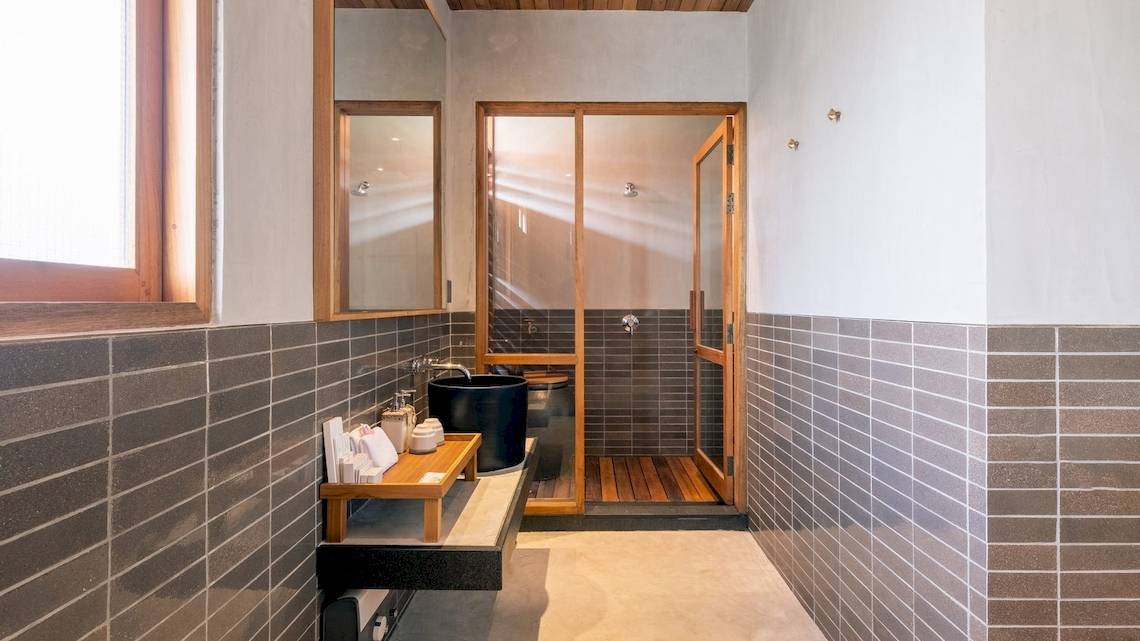Dusche Bereich im Banana Fan Sea Resort mit grauen Ziegelwänden und hölzernen Elementen.