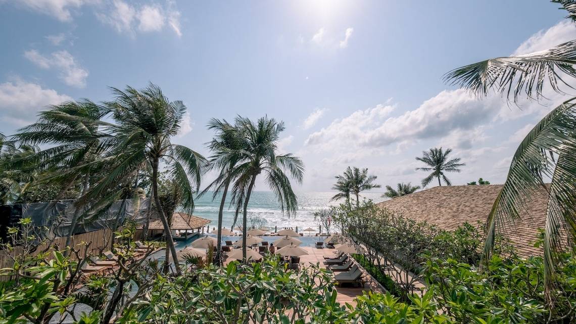 Aussicht auf den Strand des Banana Fan Sea Resorts mit Palmen und Sonnenliegen.