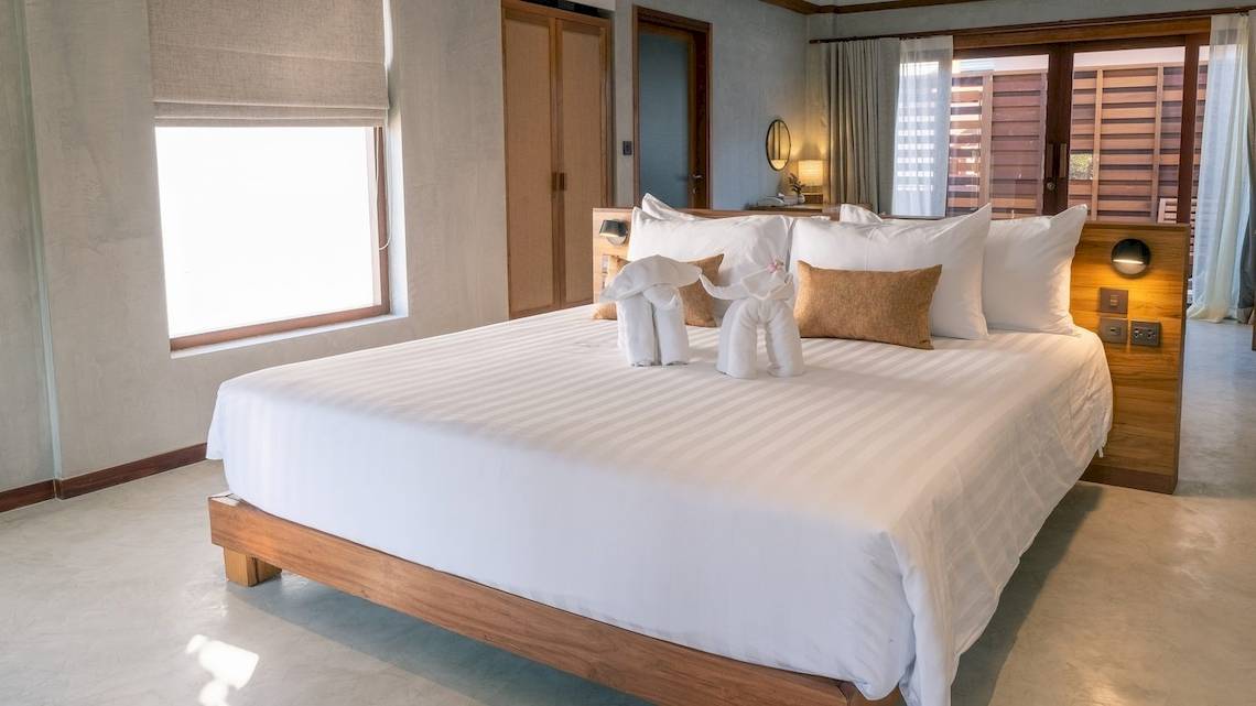 Ein stilvolles Hotelzimmer im Banana Fan Sea Resort mit einem großen Bett, weißen Laken und dekorativen Elefantenfiguren.