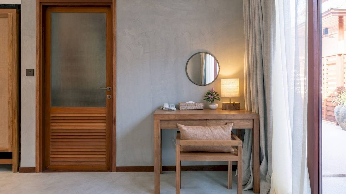 Ein schlichtes Hotelzimmer mit einem Schreibtisch, einer Lampe und einem Spiegel.