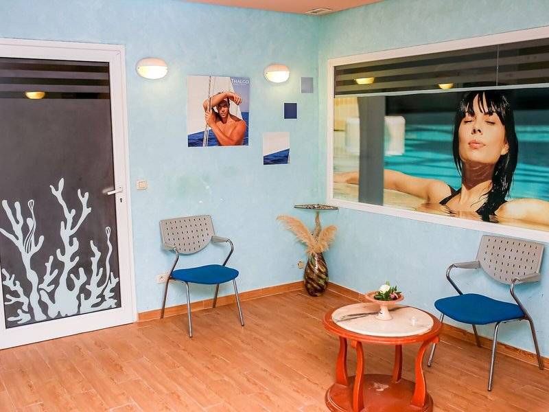 Innenansicht eines Zimmers im Mahdia Palace Thalasso mit blauen Wänden, zwei Stühlen, einem Tisch und einem großen Wandbild.