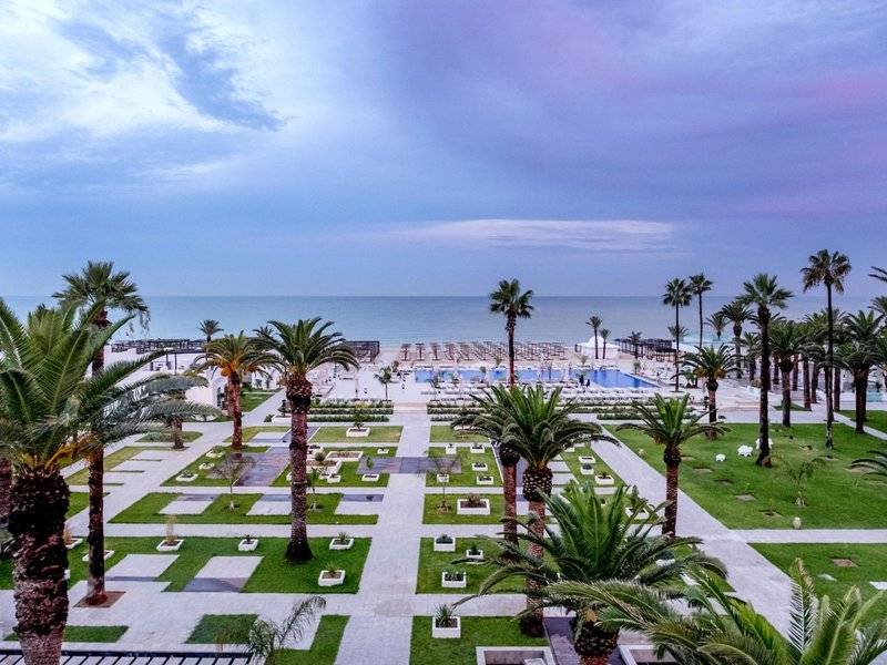 Aussicht auf das The Orangers Garden Villas & Bungalows mit Palmen und Swimmingpools am Strand