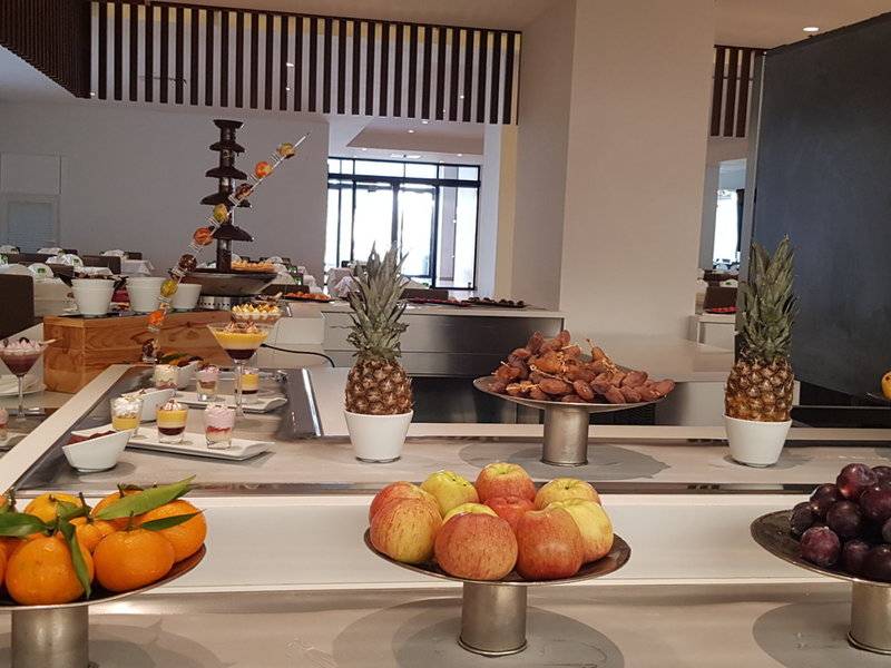 Buffet-Tisch im Orangers Garden Villas & Bungalows mit verschiedenen Früchten, Desserts und einer Schokoladenfontäne.