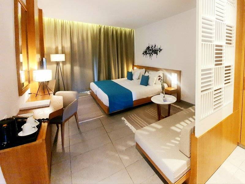 Ein modernes Schlafzimmer mit einem großen Bett, einem Schreibtisch und einem Sofa im Hotel Orangers Garden Villas & Bungalows.
