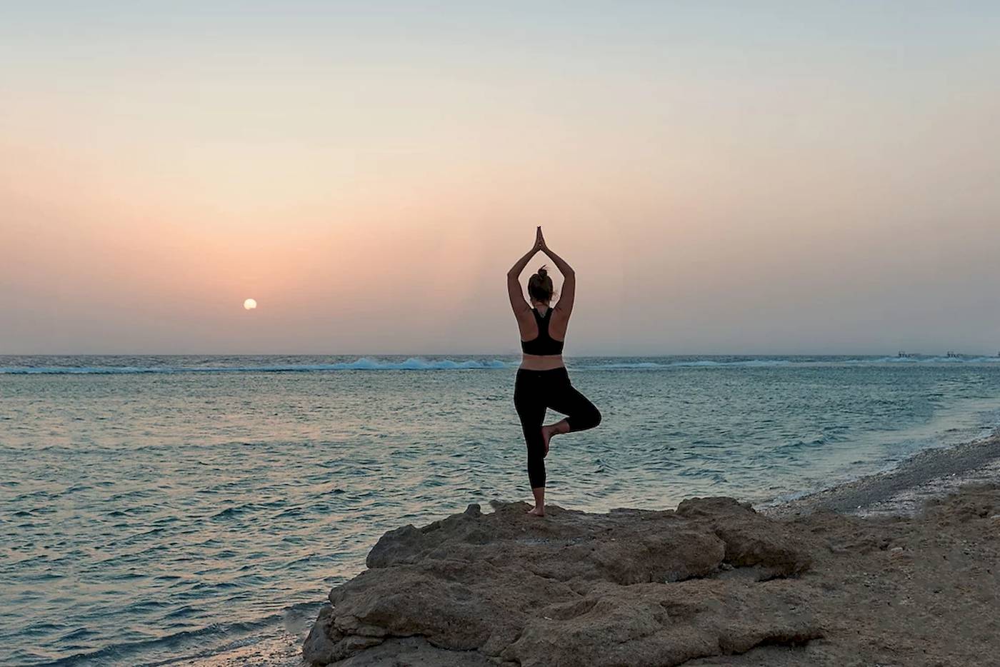 Frau macht Yoga am Strand des Mövenpick Resorts El Quseir.