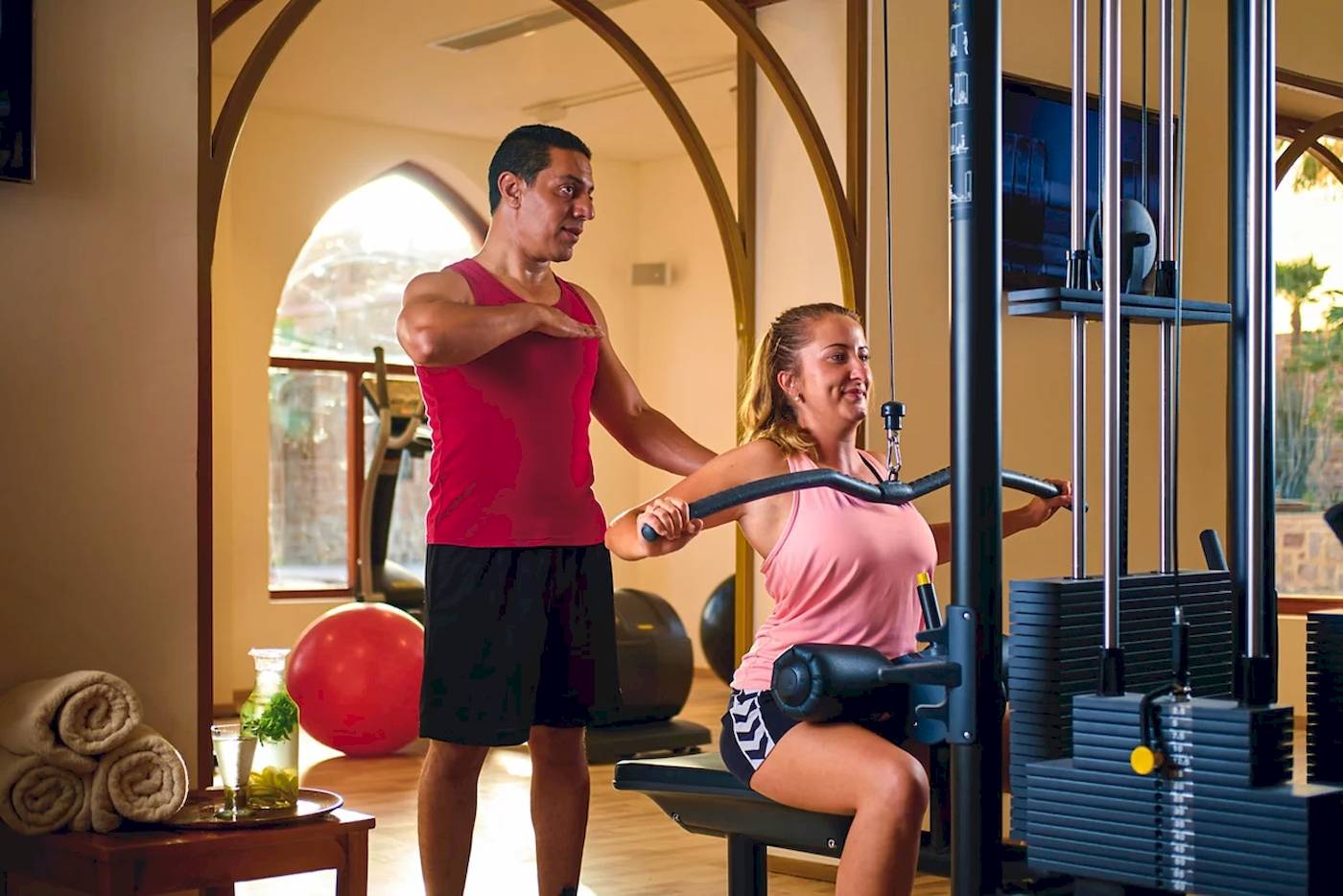 Ein Fitnesstrainer hilft einer Frau im Gym, die ein Trainingsgerät benutzt.
