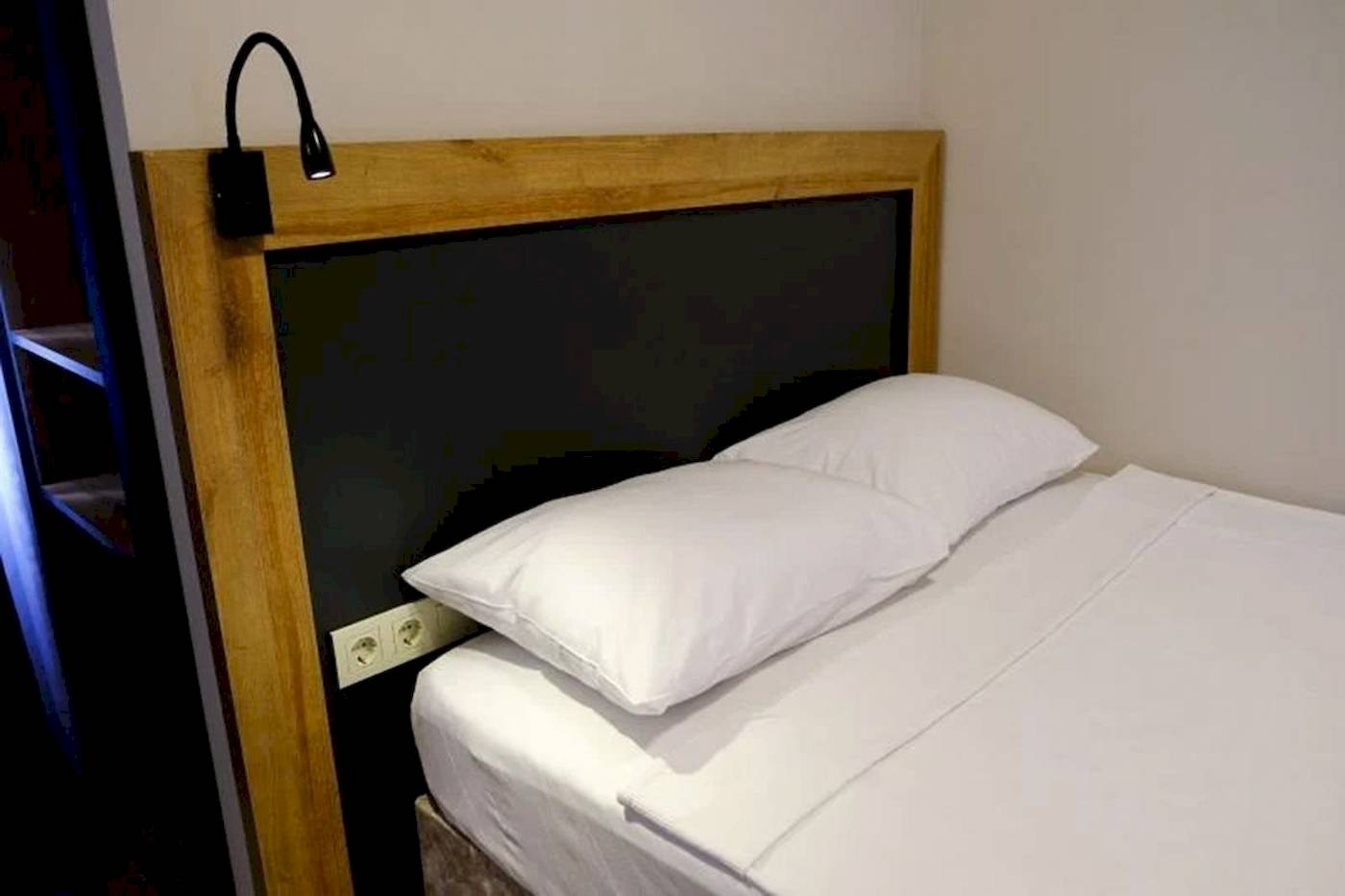 Bett im Club Wasa Holiday Village Hotel mit zwei weißen Kissen und Kopfteilbeleuchtung.