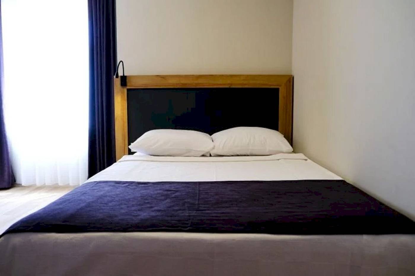 Doppelbett im Schlafzimmer des Club Wasa Holiday Village mit zwei weißen Kissen und blauer Decke.