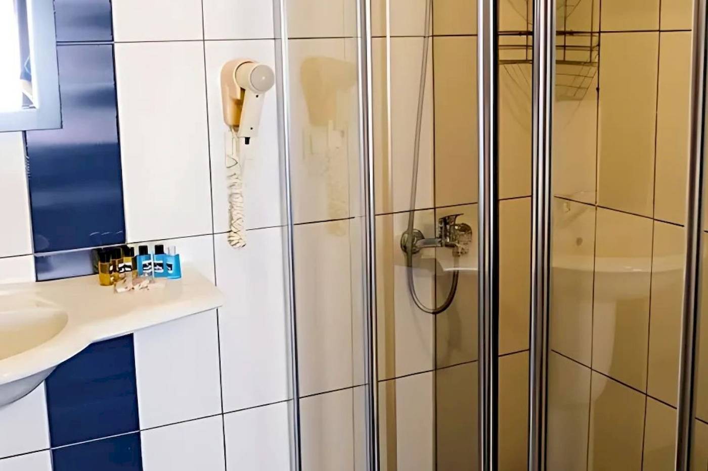 Badezimmer im Club Wasa Holiday Village mit Dusche, Waschbecken und Föhn