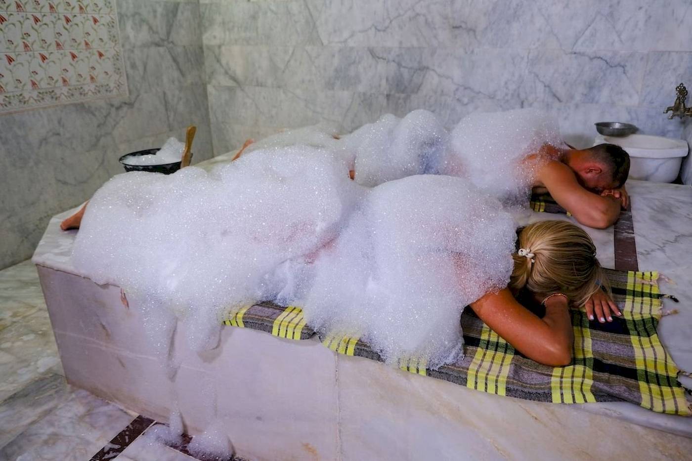 Paar im Club Wasa Holiday Village genießt ein Schaumbad in einer Marmorbadewanne.
