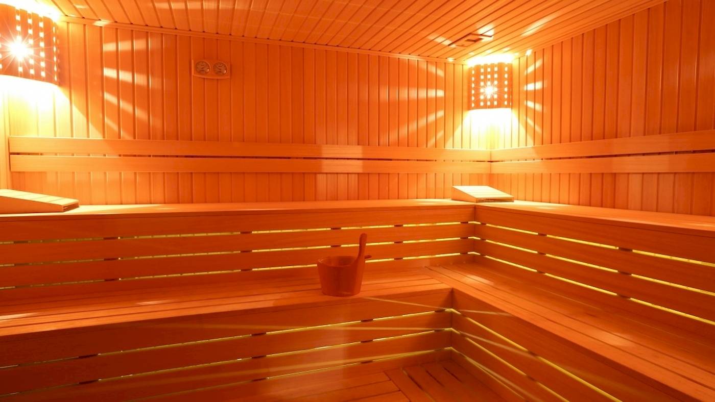 Innenansicht der Sauna im Side Star Elegance Hotel mit Holzbänken, Lichtern und einem Eimer.