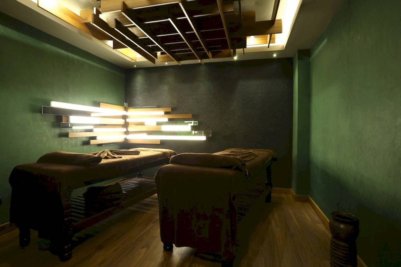 Massageraum im Side Star Elegance Hotel mit grünen Wänden und Holzboden.